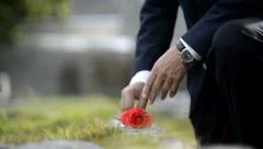 Man lays flower on grave