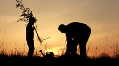 Father and son planting a tree. Sunrise. Silhouette. Spring.
