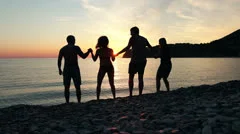 Group of people dancing on the beach at sunset, group of happy young people danc