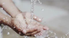 Stream of fresh water and the hands of a child from a poor community