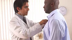 Mexican doctor using stethoscope to listen to African American patient