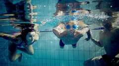 Happy and attractive mixed race family swimming underwater smiling at the camera