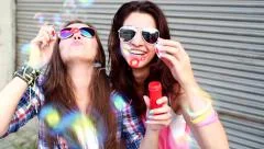 Cheerful hipster girls with sunglasses having fun making bubbles