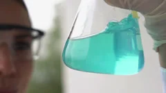 Scientist mixing chemicals in erlenmeyer flask, super slow motion HD