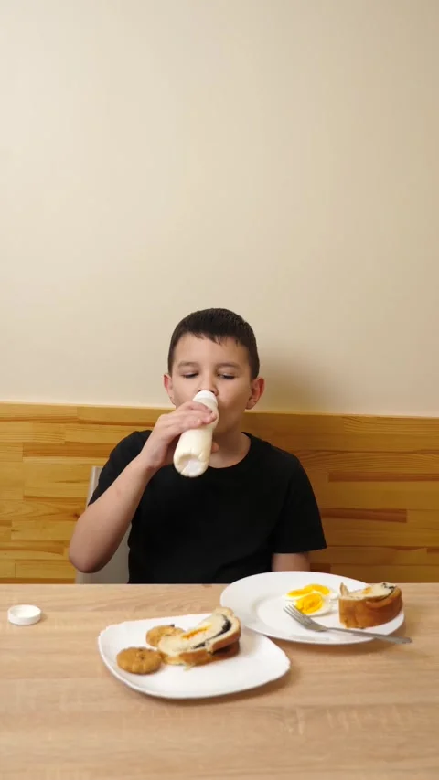 02A guy eats pastries, drinks tea and yogurt while sitting at a table. Stock Footage 313593736