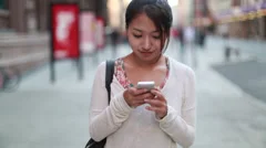 Asian woman in city walking talking texting cellphone smart phone
