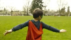 Superhero Boy Runs Around Park Pretending To Fly