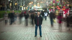 The man stands in the blurred silhouette crowd, time lapse