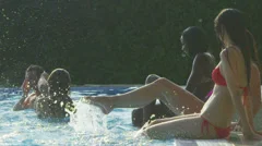 Friends enjoying summer pool party splashing and kicking legs in the water