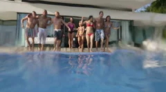 Happy fun loving group of friends running and jumping into luxury swimming pool