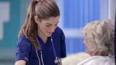 Caring nurse chats with an elderly female patient on a hospital ward.