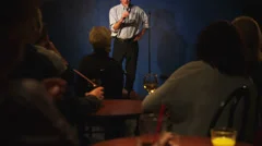 A middle aged man stands on stage and does stand up