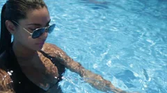 A girl in a pool party smiling looking happy wearing bikini and sun glasses
