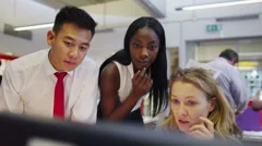 Attractive diverse business group in modern office looking at a computer screen