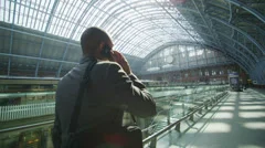 Businessman makes a phone call as he walks through iconic London railway station