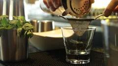A bar tender prepares the bar drink, strain in a glass beaker