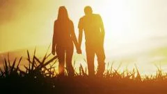 Young Couple Man Woman Walking Toward Sunset Silhouettes