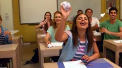 Laughing students throwing paper in classroom