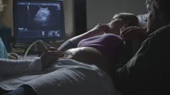 Pregnant Caucasian couple watching ultrasound
