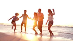 Friends dancing on beach in sunset