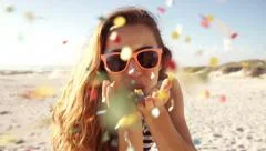 Young Woman blowing colorful confetti at the beach