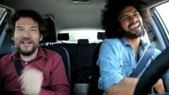 Two happy men having fun in car dancing and singing