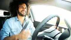 Man dancing singing and driving happy in car during sunset