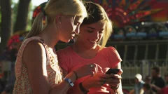 MS Two girls (16-17) using mobile phone in amusement park / American Fork City,