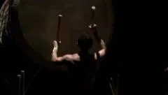 Medium shot of a taiko drummer hitting a big japanese drum