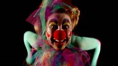 female clown is making grimaces in front of  black background