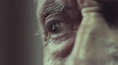 sad man sitting lonely near window: eye close-up, wrinkles and signs of aging