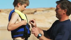 father putting life jacket on his son