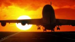 Jet plane lands on airport runway as silhouette in front of large sunset
