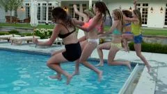 Group Of Teen Girls All Jump Into Deep End Of Swimming Pool At The Same Time