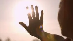Girl looks at the sun through her hand
