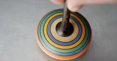 Close up shot of a spinning top moving on a silver surface