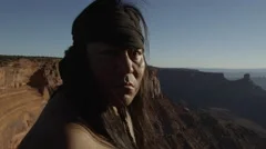 4K Native American man stares at camera on cliff's edge