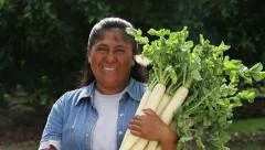 Hispanic, Latino,woman holds vegetables and smiles to camera with butterfly