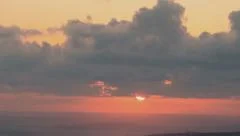 Sunset through clouds into the ocean