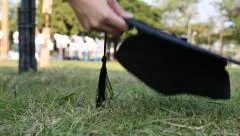 woman collect soil the graduation cap on the grass, outdoors on campus -Dan