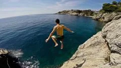 Athletic Young Man Jumping From Cliff Into Ocean Sea Water Muscular Adventure