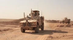 Two armored vehicles MRAP driving out military base, Afghanistan