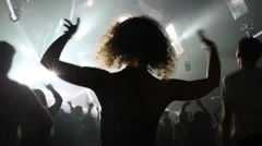 Back of woman dancing in crowd in night club during big party