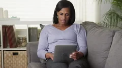 Senior black woman reading tablet ebook on couch