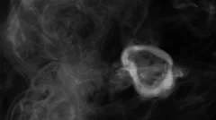 SMOKE RINGS COMING DIRECTLY AT CAMERA.  CONSISTENTLY THE SAME SIZE.  BLACK BG.