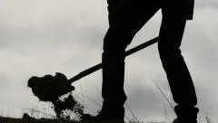silhouette of man digging a hole with a shovel slow motion close up