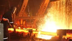 male worker cuts fiery steel blocks at the factory
