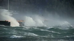 crashing waves on pier, sea spray, hurricane gale force wind storm, bird flying