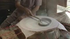 A woman pouring liquified rice paper on a steamer in Vietnam