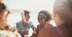 Mixed racial group of friends relaxing with beer on beach